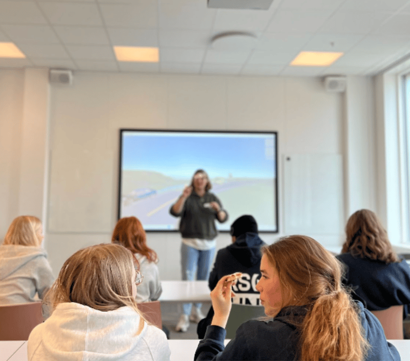 Unge mennesker i front av bildet på workshop, skjerm og leder av workshop er uklare i bakgrunnen.