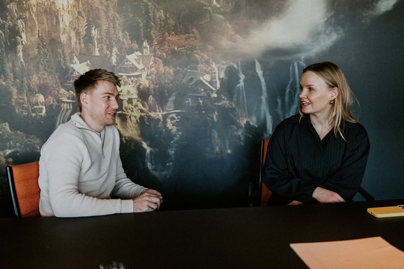 To kolleger i samtale rundt et møtebord på et kontor hos Webstep.
