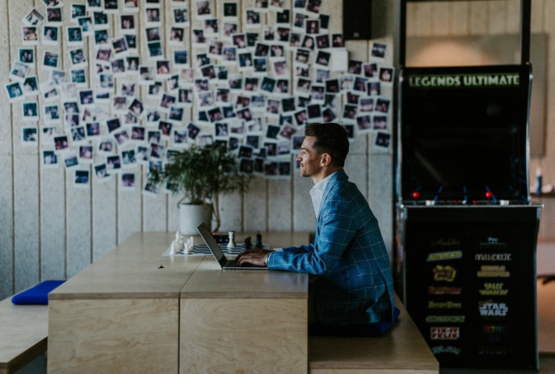 En person sitter ved et bord og jobber på en bærbar PC i et kontormiljø.